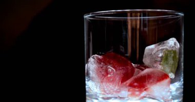 Barmen, bir parti için çeşitli içecekler (kokteyller) hazırlar. Disko veya evde barda meyve soğuk içecekler siyah arka planda görülür.