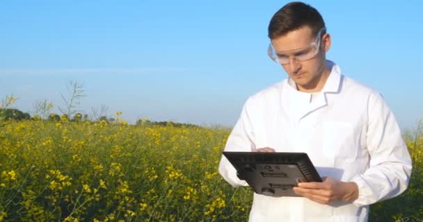 一个年轻的英俊 生物学家或农艺师 采取分析水分叶 Dna 移液器 在白色外套 护目镜 蓝色橡胶手套 走过苹果树 英俊的生物学家或农学家在白色医服 — 图库视频影像