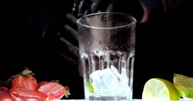 Barmen, bir parti için çeşitli içecekler (kokteyller) hazırlar. Disko veya evde barda meyve soğuk içecekler siyah arka planda görülür.