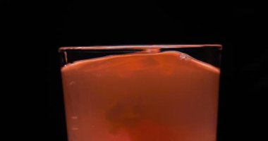 Barmen, bir parti için çeşitli içecekler (kokteyller) hazırlar. Disko veya evde barda meyve soğuk içecekler siyah arka planda görülür.