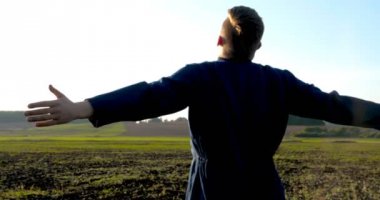 Yeşil ve sarı bokeh arka plan ile verimli topraklarda büyüyen çiftçi ve besleyici ağaç elleri. Genç bir adam (adam), çalışan üniformalı bir çiftçi, lastik çizmeler bir alanda yürüyor. Kavramı: Özgürlük, Kauçuk çizmeler, Yaşam Tarzı, Çiftçi.