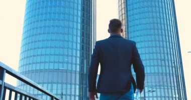 Genç bir adam (erkek) mimar, takım elbiseli bir işadamı, elinde tabletli bir klasör (cep telefonu) olan bir ceket içinde inşaat alanını ve iş binasını çeşitli eylemlerle kontrol ediyor..