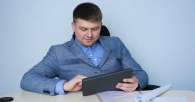 Genç bir adam (erkek) mimar, takım elbiseli bir işadamı, elinde tabletli bir klasör (cep telefonu) olan bir ceket içinde inşaat alanını ve iş binasını çeşitli eylemlerle kontrol ediyor..