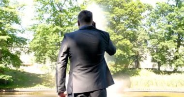 Genç yakışıklı adam (adam) işadamı ayakta (oturan) bir takım elbiseli bir ağacın yanında. Elinde siyah bir çantayla merdivenleri tırmanıyor. Konsept: iş, takım elbise, adam, adam, çanta, işadamı.