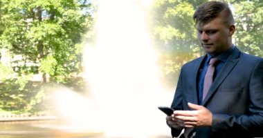 Genç yakışıklı adam (adam) işadamı ayakta (oturan) bir takım elbiseli bir ağacın yanında. Elinde siyah bir çantayla merdivenleri tırmanıyor. Konsept: iş, takım elbise, adam, adam, çanta, işadamı.