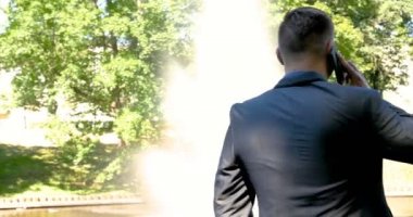 Genç yakışıklı adam (adam) işadamı ayakta (oturan) bir takım elbiseli bir ağacın yanında. Elinde siyah bir çantayla merdivenleri tırmanıyor. Konsept: iş, takım elbise, adam, adam, çanta, işadamı.