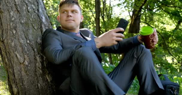 Młody Przystojny Facet Człowiek Biznesmen Stojący Siedzący Przez Drzewo Garniturze — Wideo stockowe