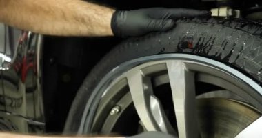 Profesyonel lastik değiştirici, çeşitli araçlar kullanarak araç sürücülerinde (lastik) korumayı değiştirir. Bir araba servisinde çalışan bir kriko üzerinde bir araba yükseltir (düşürür). Konsept: Oto oto yıkama, Araba Garajı, Araçlar, Bakım.