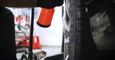 Profesyonel lastik değiştirici, çeşitli araçlar kullanarak araç sürücülerinde (lastik) korumayı değiştirir. Bir araba servisinde çalışan bir kriko üzerinde bir araba yükseltir (düşürür). Konsept: Oto oto yıkama, Araba Garajı, Araçlar, Bakım.