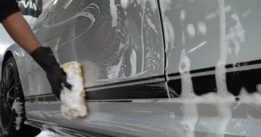 Profesyonel bir oto yıkama, bir araba yıkama ustası Karcher ve paçavra kullanarak tamamen beyaz bir bez yıkar. Yıkadıktan sonra, damlaların nasıl aktığını görebilirsiniz. Konsept: Balmumu, Seramik, Kimya.