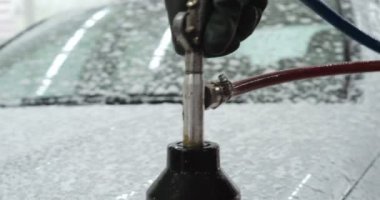 Profesyonel bir oto yıkama, bir araba yıkama ustası Karcher ve paçavra kullanarak tamamen beyaz bir bez yıkar. Yıkadıktan sonra, damlaların nasıl aktığını görebilirsiniz. Konsept: Balmumu, Seramik, Kimya.