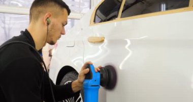 Profesyonel adam (adam) ile kulaklık ve çalışan bir üniforma parlatma aracı ile araba gövdesi parlatır. Konsept: Master Class, araba ferahlık, garaj Servisi, özel araçlar.