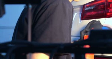 Profesyonel adam (adam) ile kulaklık ve çalışan bir üniforma parlatma aracı ile araba gövdesi parlatır. Konsept: Master Class, araba ferahlık, garaj Servisi, özel araçlar.