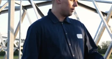 Bir elektrikçi veya Oluşturucusu ve mühendis, sarı ve beyaz kask içinde mavi bir elbise içinde güç için teknik genel bakış kontrol, elektrik direkleri, bir elektrik Kulesi, enerji ve işçi hazırlamak.