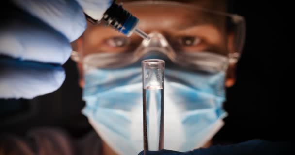 实验室工人科学家实验室助理测试化学物质在试管中的反应 干扰不同的物质 并获得视觉反应 穿着工作服的男医生戴着带护目镜的手套在体外检查 — 图库视频影像