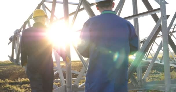一个电工或建设者和工程师 在蓝色长袍 在一个黄色和白色的头盔 检查强度的技术概述 准备电线杆 能源和工人 — 图库视频影像