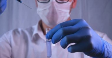 Laboratuar çalışması, Doktor bir pipet tutan, bir tıbbi maske ve gözlük, mavi kauçuk eldiven bir test tüpü bir test alır, analiz, kan, DNA, bir test tüp tutucu.