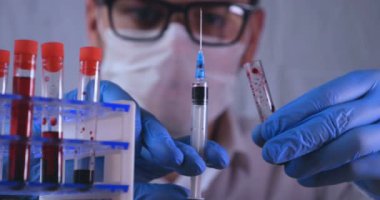 Laboratuar çalışması, Doktor bir pipet tutan, bir tıbbi maske ve gözlük, mavi kauçuk eldiven bir test tüpü bir test alır, analiz, kan, DNA, bir test tüp tutucu.