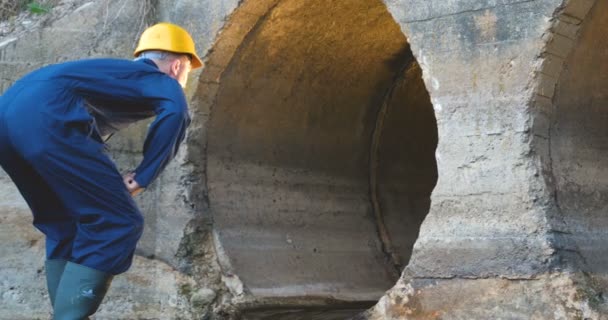 Engenheiro Trabalhador Verifica Calhas Roupão Azul Botas Capacete Amarelo Construção — Vídeo de Stock