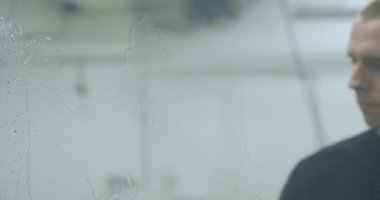 Genç bir profesyonel adam (erkek) pencere temizleyici, Windows ve çeşitli aksesuarlar için köpük ve deterjanlar kullanır, sonra iyice siliyor. Kavramı: glitter pencere, deterjanlar.