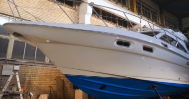 Yavaş hareket profesyonel bir adam (adam) bir garaj (hizmet) bir kazak giymiş çalışma giysileri içinde bir boya tabancası (püskürtme tabancası) ayarlar ve (seramik bir tabaka koyarak) bir yat boyama başlar.