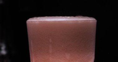 Barmen, bir parti için çeşitli içecekler (kokteyller) hazırlar. Disko veya evde barda meyve soğuk içecekler siyah arka planda görülür.