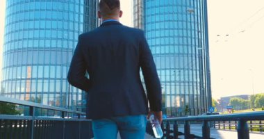 Genç bir adam (erkek) mimar, takım elbiseli bir işadamı, elinde tabletli bir klasör (cep telefonu) olan bir ceket içinde inşaat alanını ve iş binasını çeşitli eylemlerle kontrol ediyor..