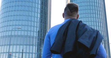 Genç bir adam (erkek) mimar, takım elbiseli bir işadamı, elinde tabletli bir klasör (cep telefonu) olan bir ceket içinde inşaat alanını ve iş binasını çeşitli eylemlerle kontrol ediyor..