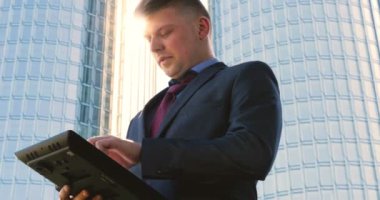 Genç bir adam (erkek) mimar, takım elbiseli bir işadamı, elinde tabletli bir klasör (cep telefonu) olan bir ceket içinde inşaat alanını ve iş binasını çeşitli eylemlerle kontrol ediyor..