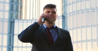 Genç bir adam (erkek) mimar, takım elbiseli bir işadamı, elinde tabletli bir klasör (cep telefonu) olan bir ceket içinde inşaat alanını ve iş binasını çeşitli eylemlerle kontrol ediyor..