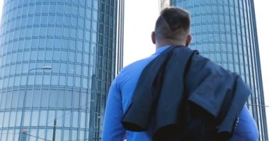 Genç bir adam (erkek) mimar, takım elbiseli bir işadamı, elinde tabletli bir klasör (cep telefonu) olan bir ceket içinde inşaat alanını ve iş binasını çeşitli eylemlerle kontrol ediyor..