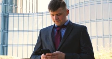 Genç bir adam (erkek) mimar, takım elbiseli bir işadamı, elinde tabletli bir klasör (cep telefonu) olan bir ceket içinde inşaat alanını ve iş binasını çeşitli eylemlerle kontrol ediyor..