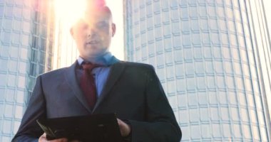 Genç bir adam (erkek) mimar, takım elbiseli bir işadamı, elinde tabletli bir klasör (cep telefonu) olan bir ceket içinde inşaat alanını ve iş binasını çeşitli eylemlerle kontrol ediyor..