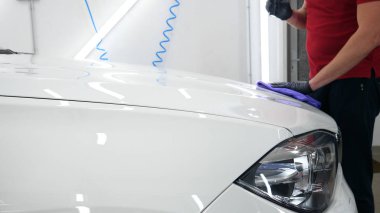 Profesyonel işçi elinde beyaz bir sünger tutar, sıvı, oto tamir dükkanı, araba yıkama uygular, bir araç garaj parlatma ve boyama sonra bir el feneri ile bir araba kontrol.