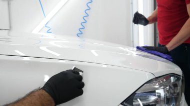 Profesyonel işçi elinde beyaz bir sünger tutar, sıvı, oto tamir dükkanı, araba yıkama uygular, bir araç garaj parlatma ve boyama sonra bir el feneri ile bir araba kontrol.