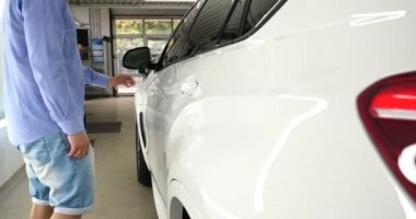 Garajda bir adam (araba servisi) araba alarmı kontrol eder ve sonra (geliyor) kapalı (açık) onun arkasındaki ışıkları açmak kapatır. Konsept: Oto Garaj, güvenlik.