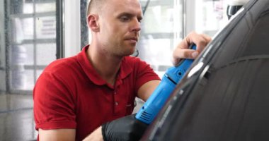 Profesyonel bir kaporta ve far cilası işçisi arabayı boyamadan veya satışa hazırlandıktan sonra taşır. Taze arabalar, Otomotiv Merkezi, Hizmet, Profesyonel.