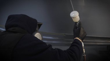 Garajda profesyonel bir adam (adam) bir mini-jet (spreyler) ile bir koruyucu takım dispenser ve koruyucu gözlük kullanarak yüzeye boya (seramik) uygulayarak yat (ulaşım) kapsar.