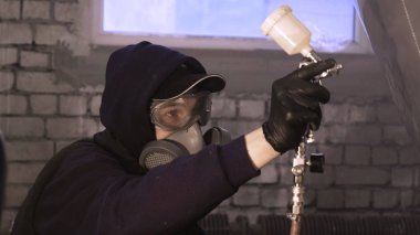 Garajda profesyonel bir adam (adam) bir mini-jet (spreyler) ile bir koruyucu takım dispenser ve koruyucu gözlük kullanarak yüzeye boya (seramik) uygulayarak yat (ulaşım) kapsar.