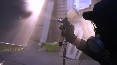 Garajda profesyonel bir adam (adam) bir mini-jet (spreyler) ile bir koruyucu takım dispenser ve koruyucu gözlük kullanarak yüzeye boya (seramik) uygulayarak yat (ulaşım) kapsar.