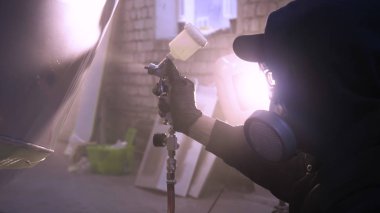 Garajda profesyonel bir adam (adam) bir mini-jet (spreyler) ile bir koruyucu takım dispenser ve koruyucu gözlük kullanarak yüzeye boya (seramik) uygulayarak yat (ulaşım) kapsar.