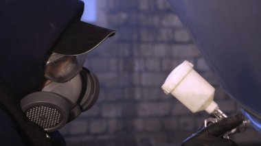 Garajda profesyonel bir adam (adam) bir mini-jet (spreyler) ile bir koruyucu takım dispenser ve koruyucu gözlük kullanarak yüzeye boya (seramik) uygulayarak yat (ulaşım) kapsar.