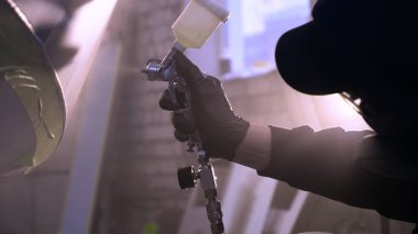 Garajda profesyonel bir adam (adam) bir mini-jet (spreyler) ile bir koruyucu takım dispenser ve koruyucu gözlük kullanarak yüzeye boya (seramik) uygulayarak yat (ulaşım) kapsar.