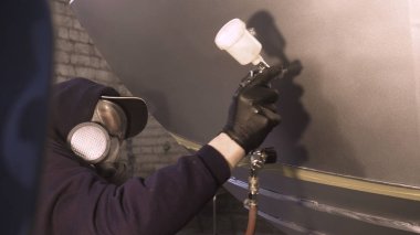 Garajda profesyonel bir adam (adam) bir mini-jet (spreyler) ile bir koruyucu takım dispenser ve koruyucu gözlük kullanarak yüzeye boya (seramik) uygulayarak yat (ulaşım) kapsar.