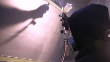 Garajda profesyonel bir adam (adam) bir mini-jet (spreyler) ile bir koruyucu takım dispenser ve koruyucu gözlük kullanarak yüzeye boya (seramik) uygulayarak yat (ulaşım) kapsar.