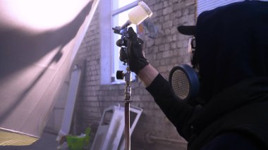 Garajda profesyonel bir adam (adam) bir mini-jet (spreyler) ile bir koruyucu takım dispenser ve koruyucu gözlük kullanarak yüzeye boya (seramik) uygulayarak yat (ulaşım) kapsar.