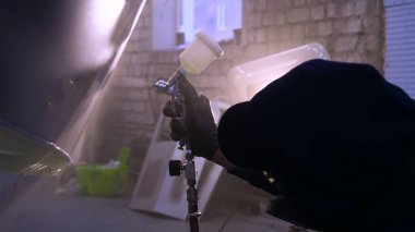 Garajda profesyonel bir adam (adam) bir mini-jet (spreyler) ile bir koruyucu takım dispenser ve koruyucu gözlük kullanarak yüzeye boya (seramik) uygulayarak yat (ulaşım) kapsar.