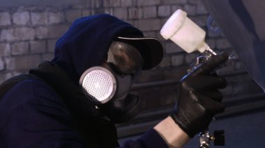 Garajda profesyonel bir adam (adam) bir mini-jet (spreyler) ile bir koruyucu takım dispenser ve koruyucu gözlük kullanarak yüzeye boya (seramik) uygulayarak yat (ulaşım) kapsar.