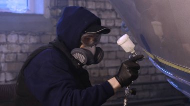 Garajda profesyonel bir adam (adam) bir mini-jet (spreyler) ile bir koruyucu takım dispenser ve koruyucu gözlük kullanarak yüzeye boya (seramik) uygulayarak yat (ulaşım) kapsar.