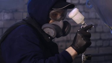 Garajda profesyonel bir adam (adam) bir mini-jet (spreyler) ile bir koruyucu takım dispenser ve koruyucu gözlük kullanarak yüzeye boya (seramik) uygulayarak yat (ulaşım) kapsar.